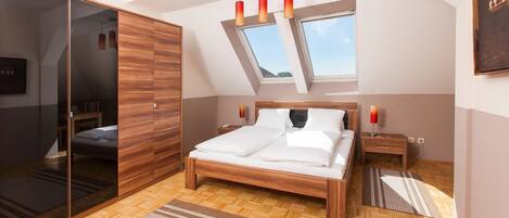 Un dormitorio moderno con cama de madera, un ventanal grande y un tragaluz.