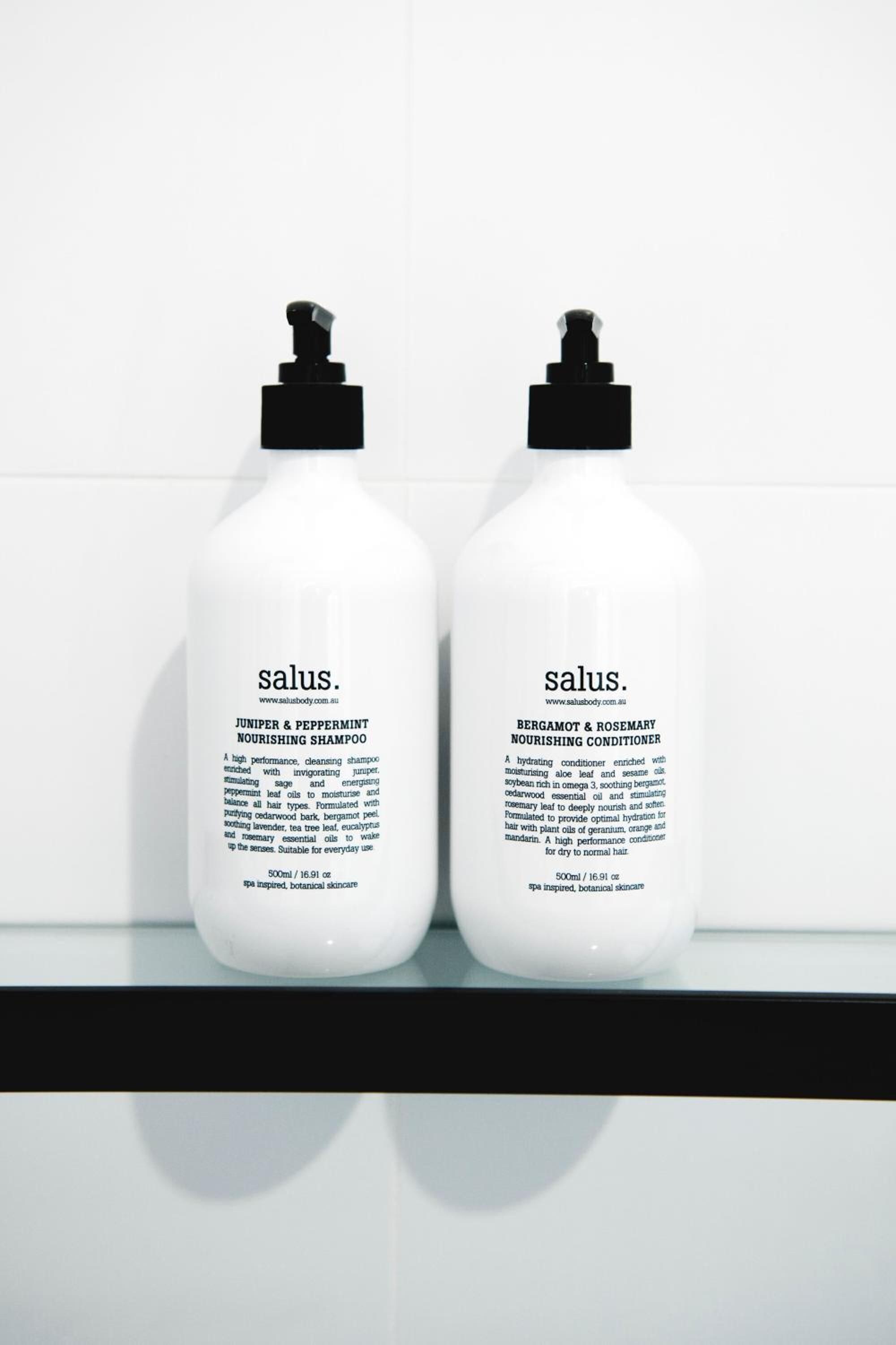 Two bottles of salus products on a white shelf against a white background.