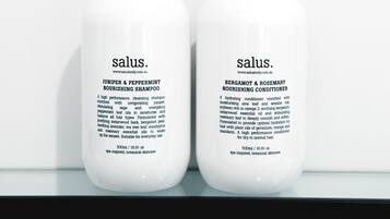 Two bottles of salus products on a white shelf against a white background.