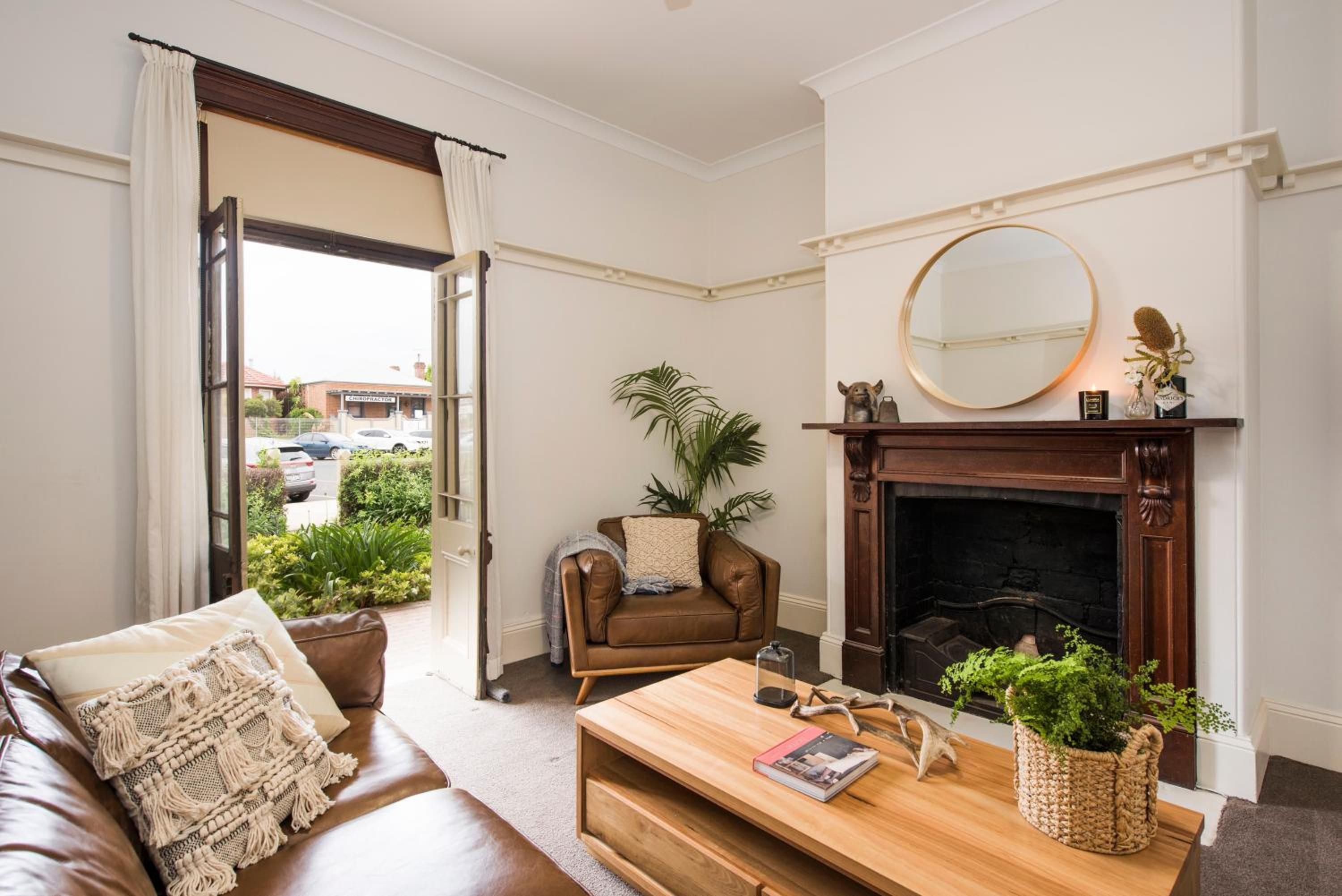 Una sala de estar con un sofá de cuero marrón, una mesa de centro de madera, una chimenea y vistas al exterior.