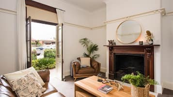 Una sala de estar con un sofá de cuero marrón, una mesa de centro de madera, una chimenea y vistas al exterior.