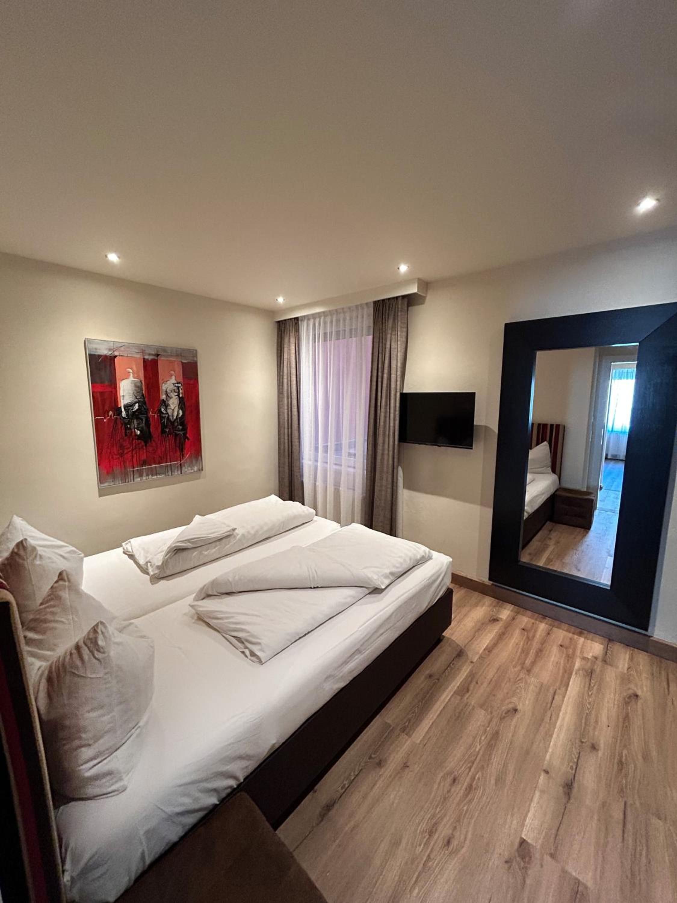 Ein modernes Schlafzimmer mit einem großen Bett, einem Flachbildfernseher und einem Spiegel.