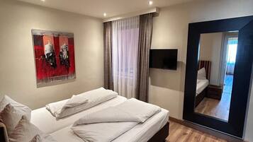 Ein modernes Schlafzimmer mit einem großen Bett, einem Flachbildfernseher und einem Spiegel.