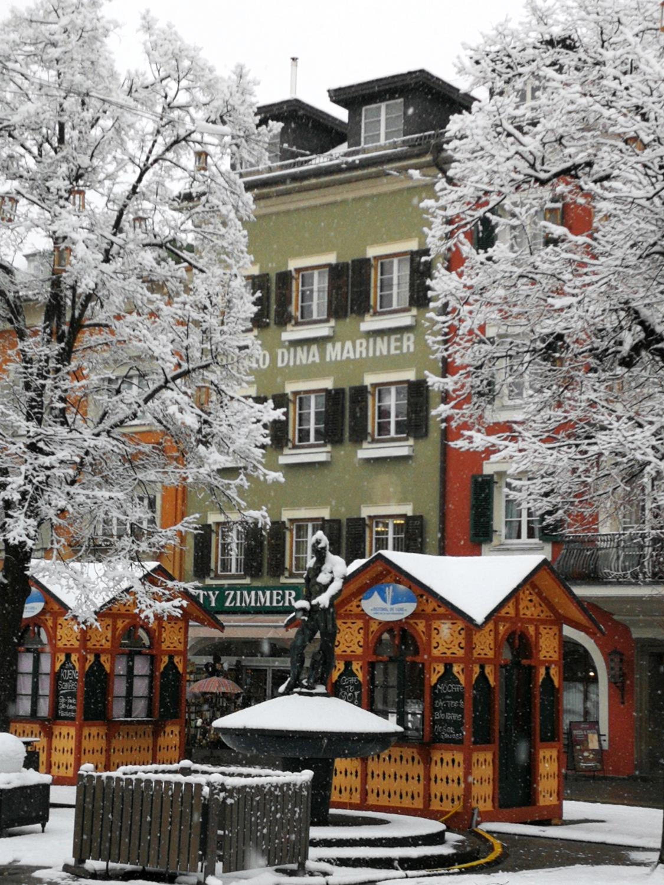 Ein Gebäude mit einem Schild, auf dem 'DINA MARINER' steht, und ein farbenfrohes Gebäude mit einem schneebedeckten Dach im Vordergrund.