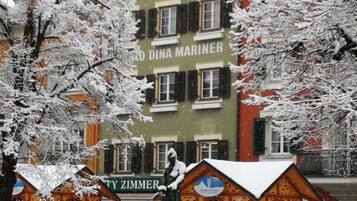 Ein Gebäude mit einem Schild, auf dem 'DINA MARINER' steht, und ein farbenfrohes Gebäude mit einem schneebedeckten Dach im Vordergrund.