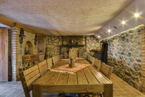 A rustic dining area with a long wooden table, benches, and a stone wall. - Savaneti Eco Hotel (Telavi)
