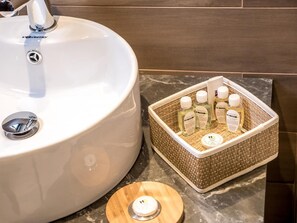 A bathroom sink with a chrome faucet and a white basin. Next to it, there is a wicker basket containing various toiletries. - Hotel Calipso Hotel (Sofia)