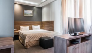A hotel room with a bed, a TV, a desk, and a small ottoman. - Hotel Calipso Hotel (Sofia)