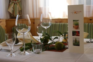 Una mesa servida con copas de vino, una vela y un atril con imágenes.