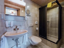 A bathroom with a sink, toilet, and a glass-enclosed shower.