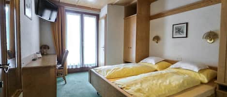 A room with a bed, a desk, a chair, a television, and a window.