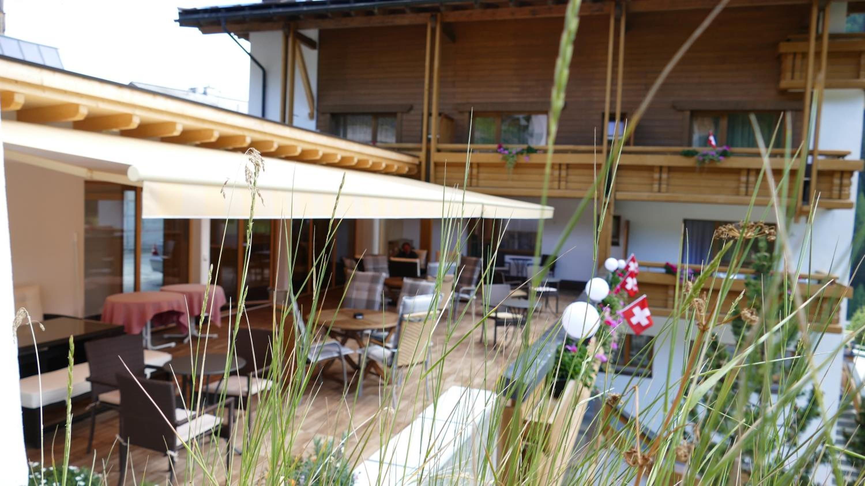 A building with a covered outdoor seating area, multiple balconies, and a dining area with tables and chairs.
