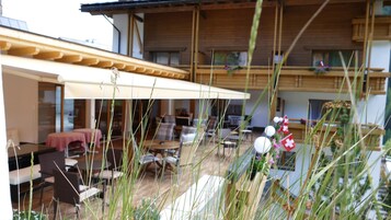 A building with a covered outdoor seating area, multiple balconies, and a dining area with tables and chairs.