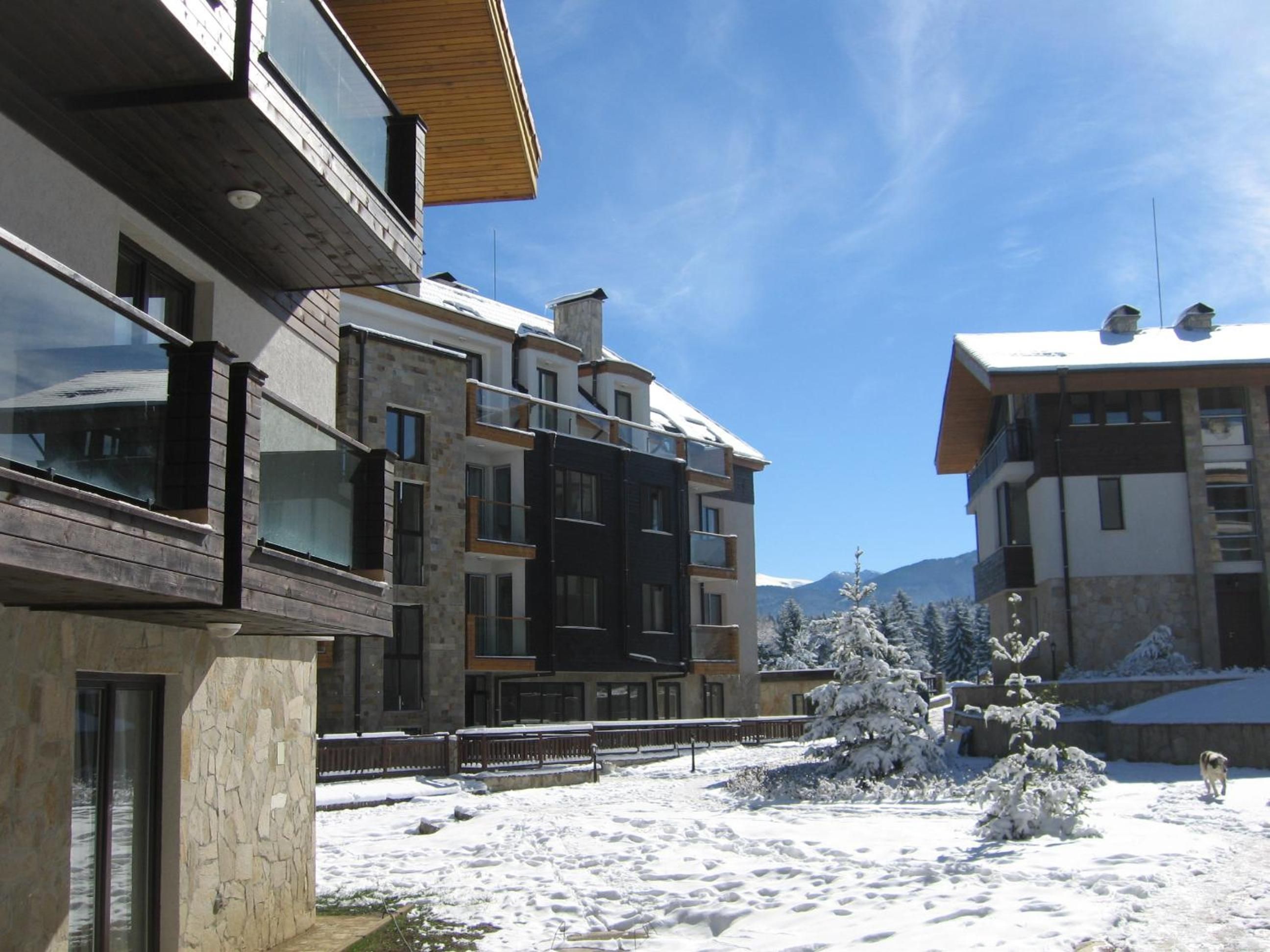 Un edificio moderno de varios pisos con balcones, fachada de piedra y paisaje nevado.