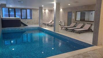 Una piscina interior con paredes de azulejos y un jacuzzi.