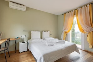 Una habitación de hotel con cama, mesitas de noche, un escritorio y una ventana con cortinas.