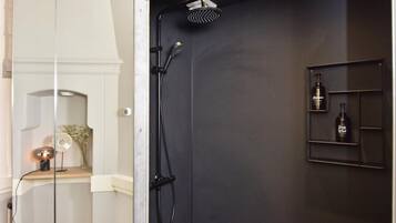 Een moderne badkamer met een douche, een wastafel met spiegel en een plank met toiletartikelen.