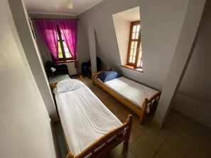 Un dormitorio con dos camas individuales, una ventana, un radiador y un escritorio.