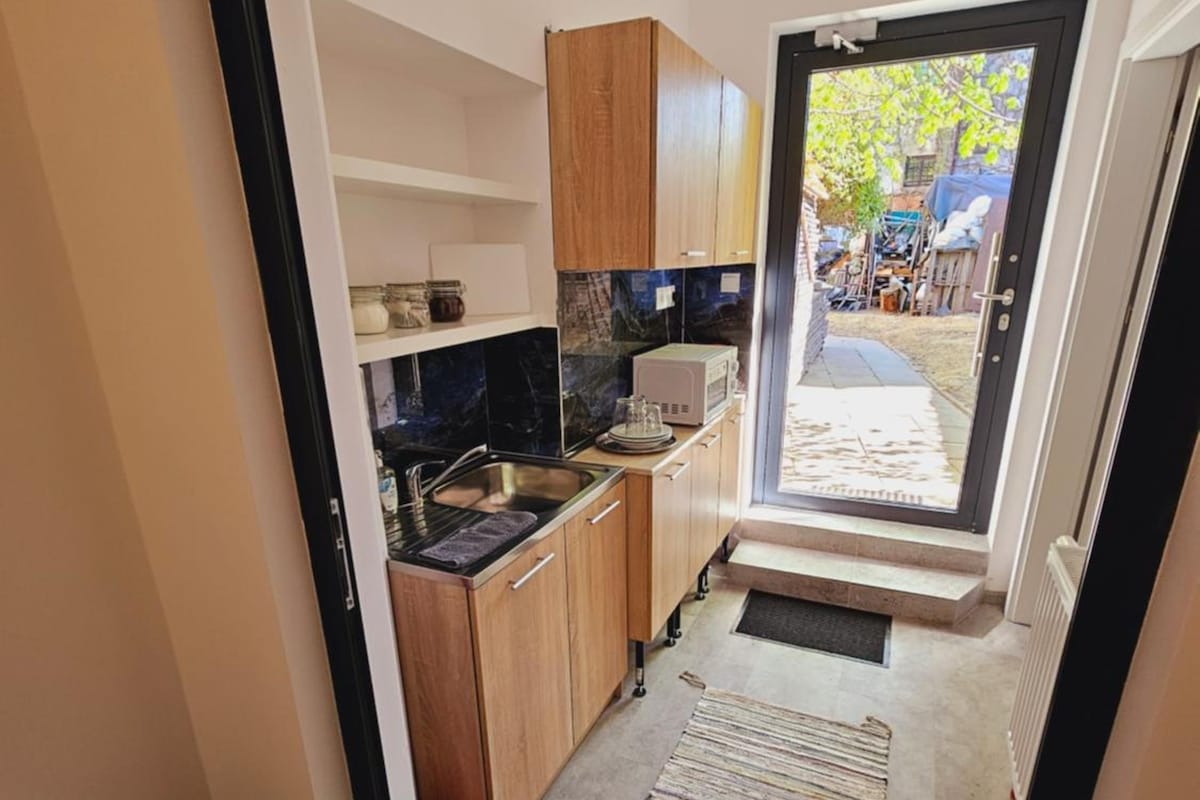 A narrow kitchen with wooden cabinets, a microwave, and a sink.
