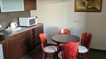 A compact kitchen with a microwave, a kettle, and a dining table with four chairs.