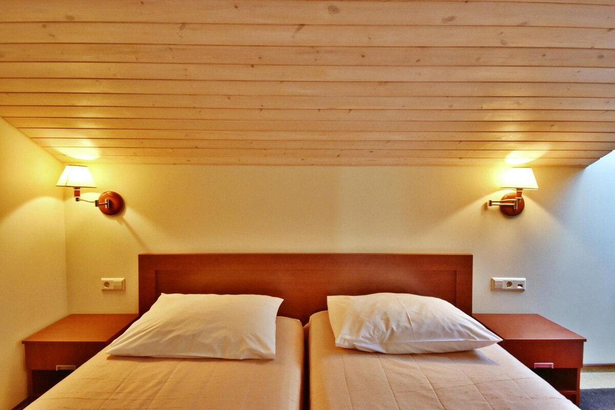 Una habitación con dos camas, cabeceros de madera y lámparas fijadas a la pared.