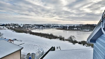 A snow-covered landscape with a river, buildings, and a clear sky.