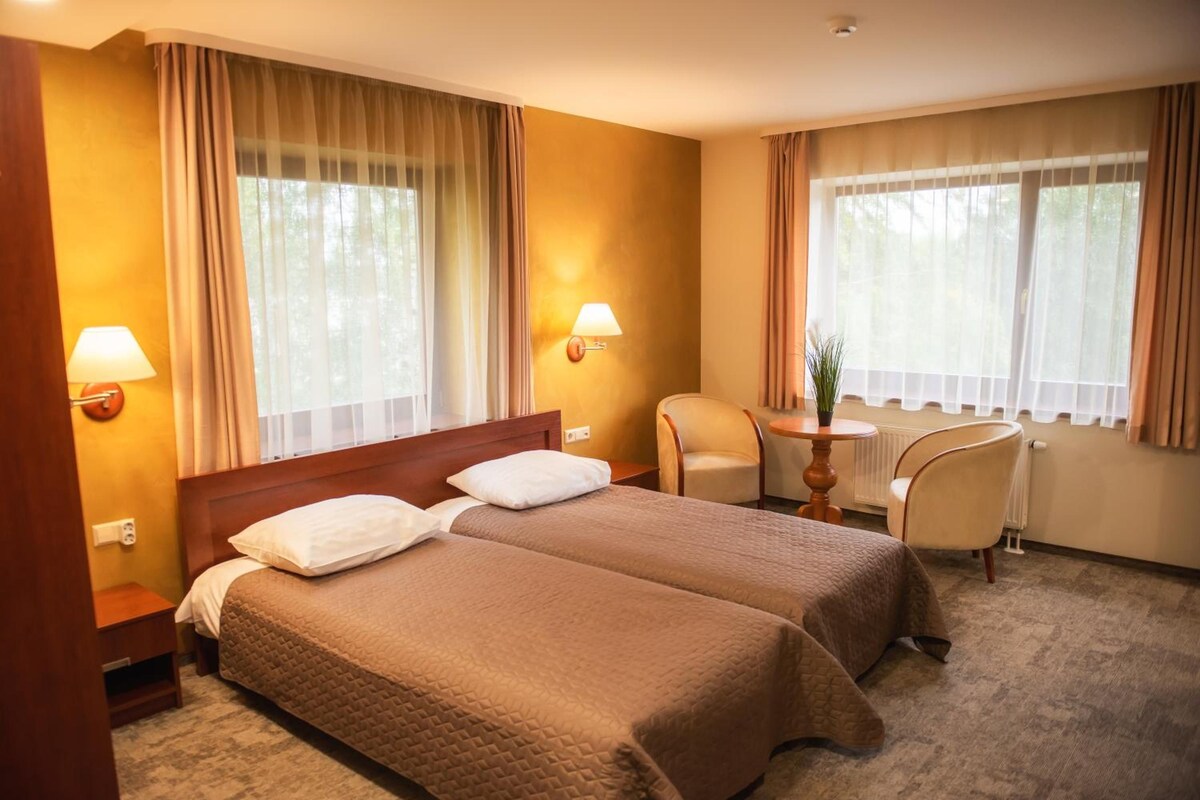 Una habitación de hotel con dos camas, un escritorio, una silla y dos lámparas.