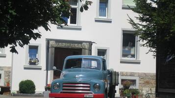 Un vecchio camioncino blu parcheggiato davanti a un edificio con facciata in pietra e numerose finestre.