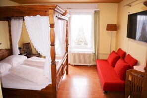 Quarto com cama de dossel, sofá vermelho e radiador.