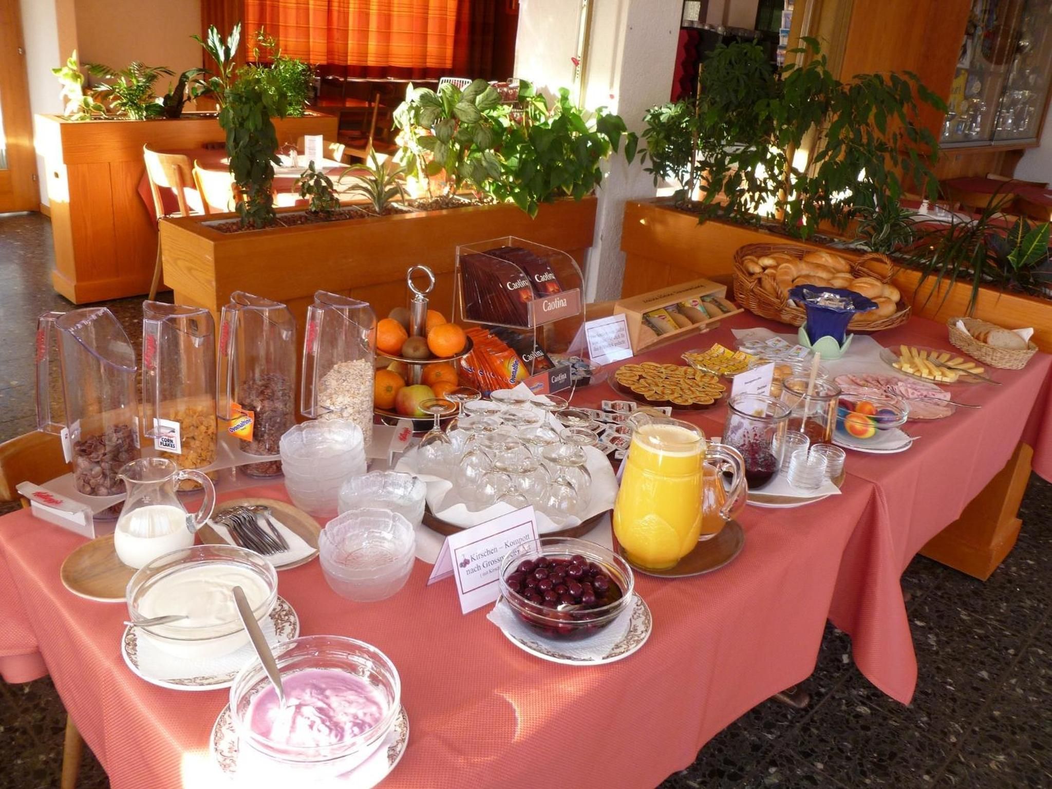 A buffet table with various food items and beverages, including fruits, bread, and dairy products.