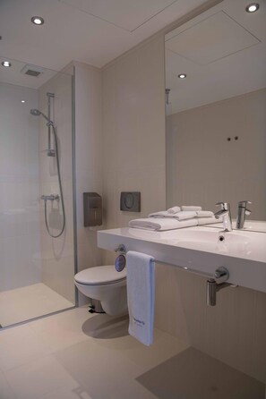 A modern bathroom with a glass-enclosed shower, a toilet, and a vanity with a mirror. - Impresamente Art Hotel (Sofia)