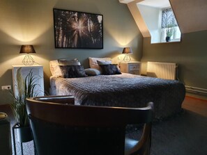 A bedroom with a bed, two bedside tables, a radiator, a window, and a painting on the wall. - Baron Frits (Kessel)