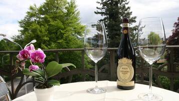 A bottle of Masi Costasera Amarone wine, two empty wine glasses, and a potted orchid on a table with a railing in the background.