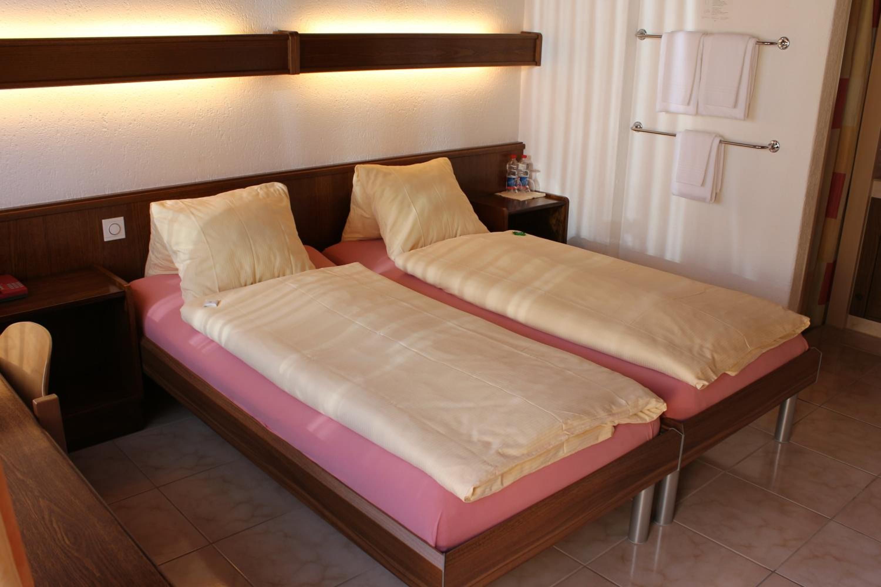 A double bed with a wooden headboard and a nightstand with a lamp.