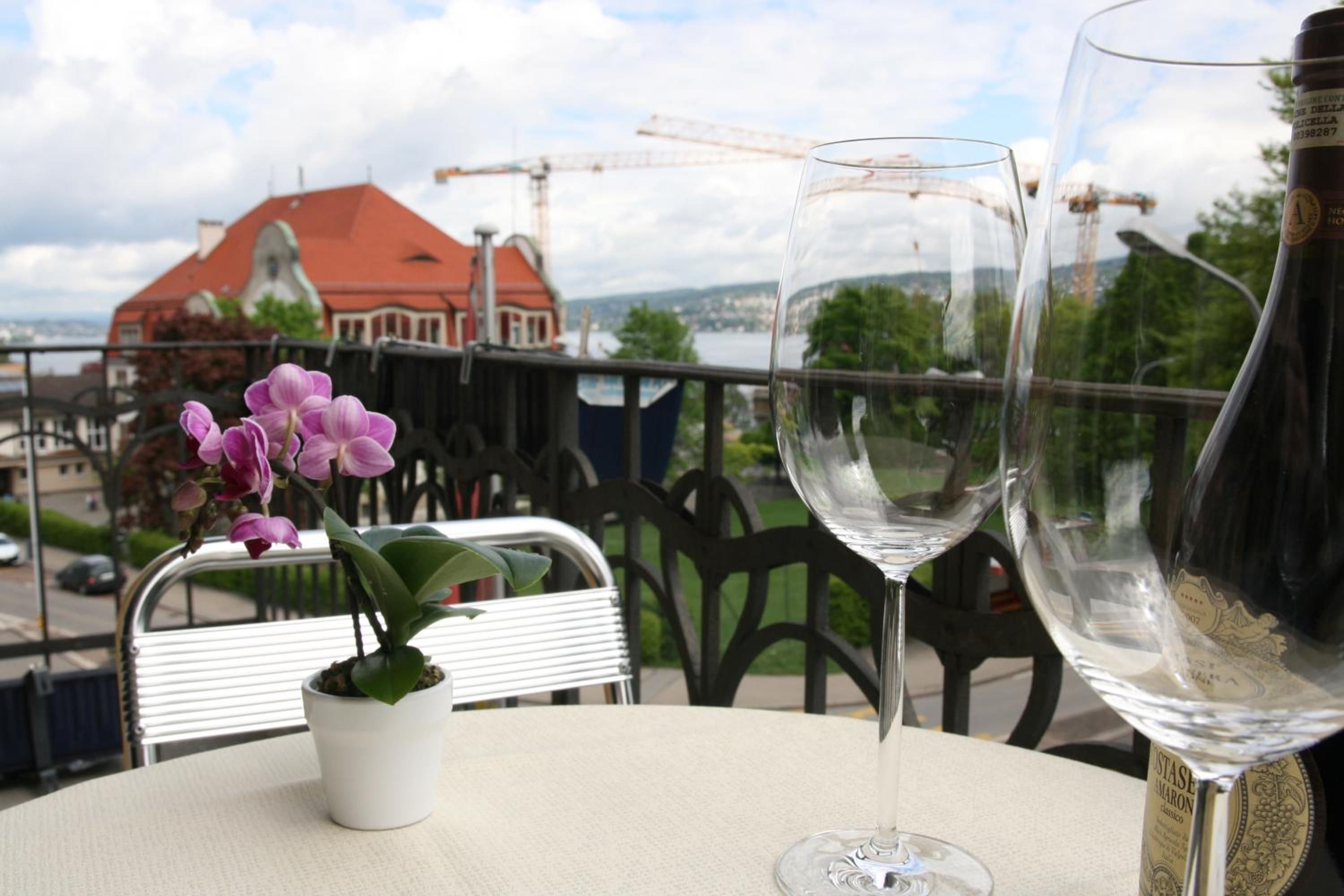 A balcony with a table, two wine glasses, and a potted orchid.