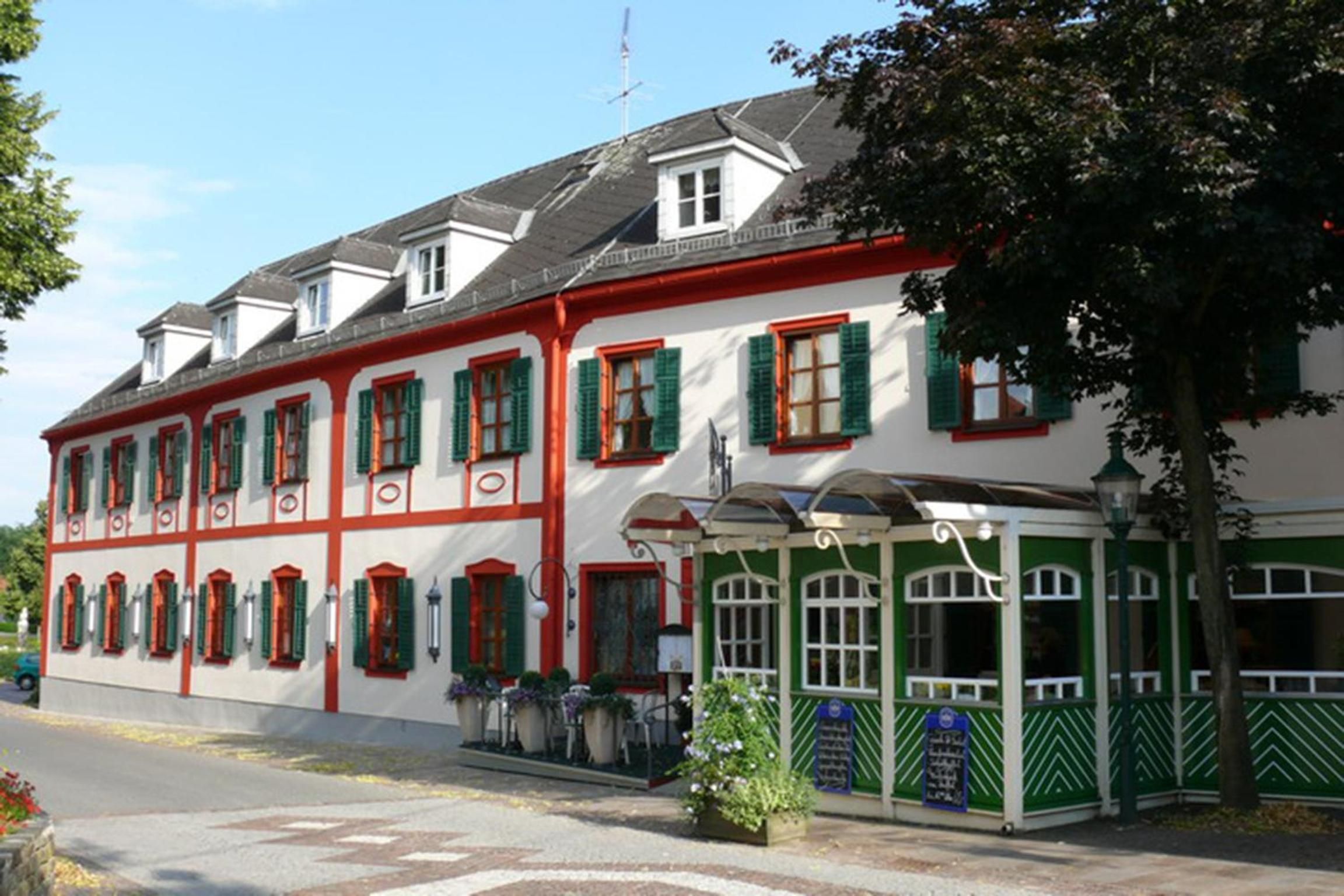 Ein traditionelles Gebäude mit zahlreichen Fenstern, einem überdachten Eingang und einer Flagge auf dem Dach.