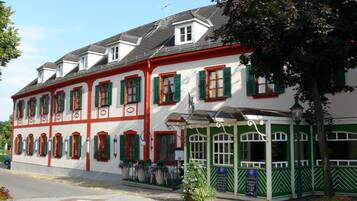 Ein traditionelles Gebäude mit zahlreichen Fenstern, einem überdachten Eingang und einer Flagge auf dem Dach.