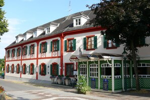 A traditional building with multiple windows, a covered entrance, and a flag on the roof. - Hotel Restaurant Fischer (Bad Waltersdorf)
