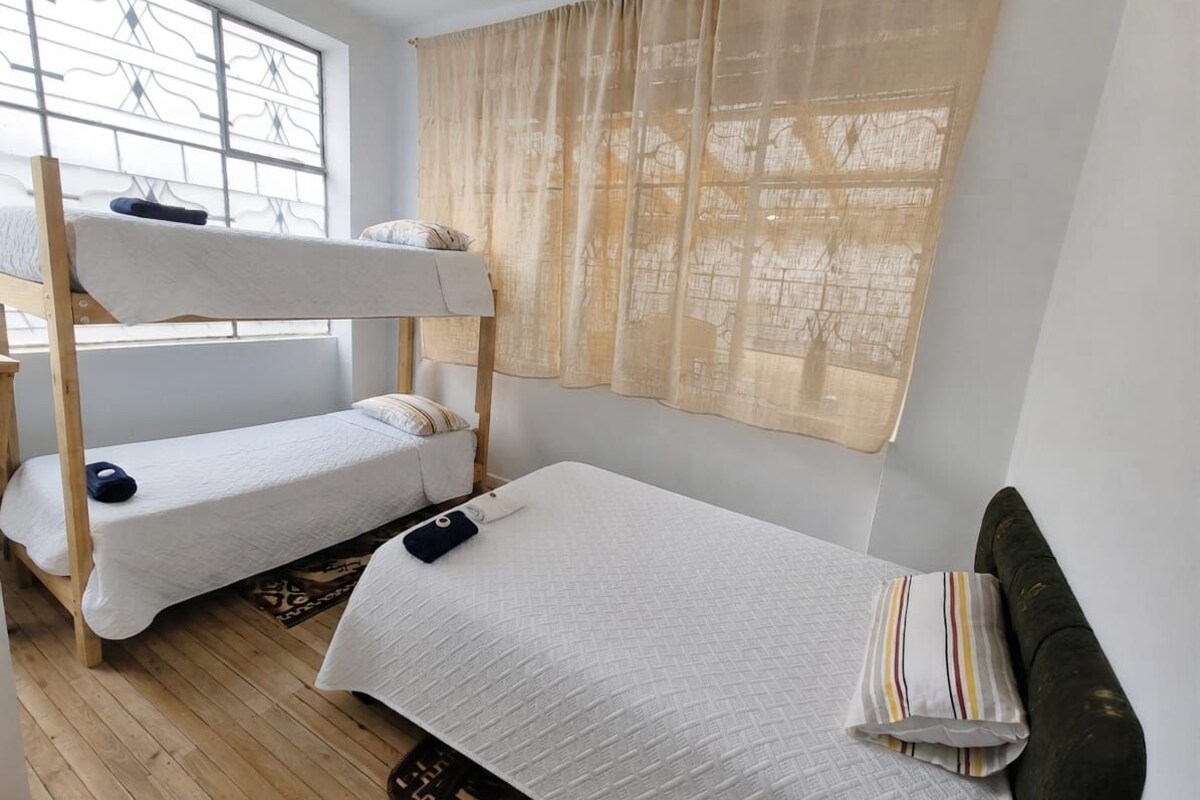 Ein Schlafsaalzimmer mit Etagenbetten, einem Fenster mit Blick und einem Vorhang.