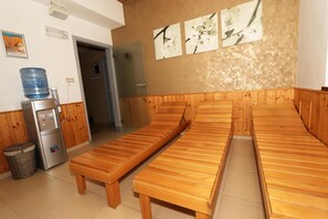 A room with wooden benches, a water dispenser, and a wall with floral artwork. - Hotel Corona (Kaplice)