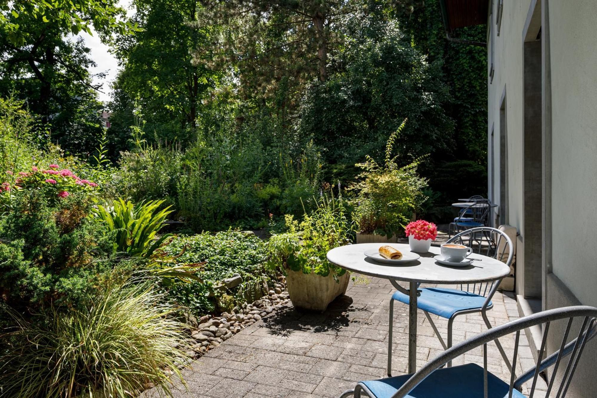 A patio with a round table, chairs, and a potted plant.