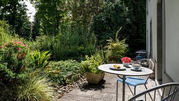A patio with a round table, chairs, and a potted plant.