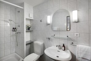 A modern bathroom with a shower, toilet, sink, and a mirror. - Hotel Lv Wen (Mönchaltorf)