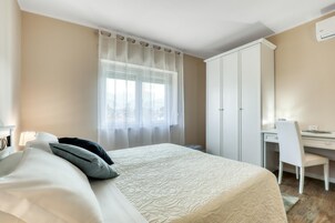 A bedroom with a bed, a desk, and a wardrobe.