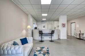 A modern interior with a white sofa, a bar area, and a dining table.