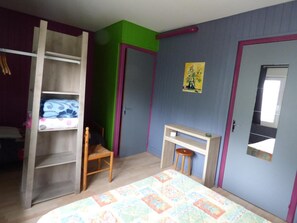 A bedroom with a bed, a wardrobe, a chair, a small table, and a door with a window. - Hotel Restaurant La Chaumiere Du Lac (Clairvaux-les-Lacs)