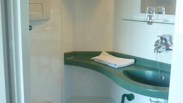 A compact bathroom with a white toilet, a green sink, and a mirror above the sink.