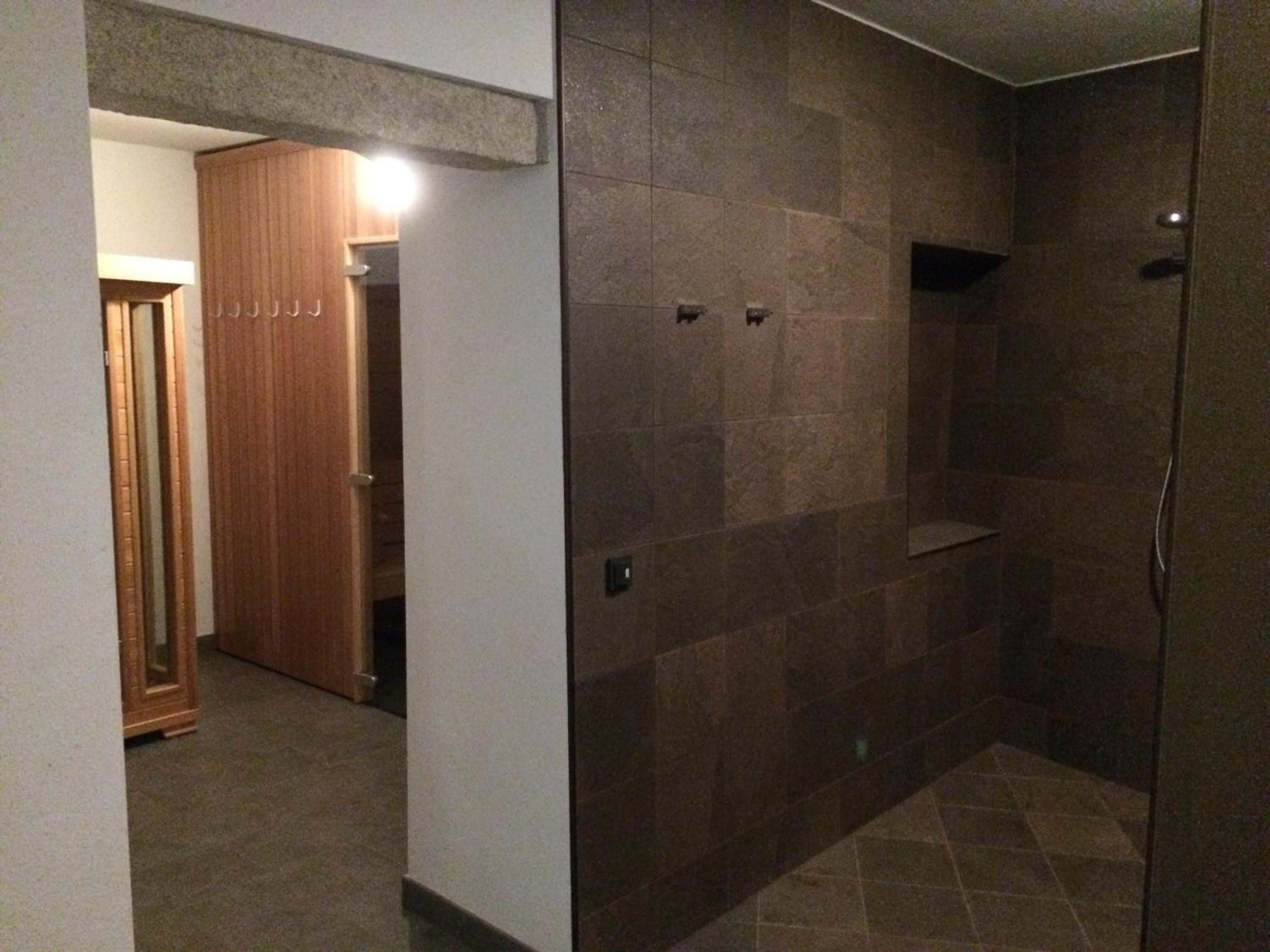 Une salle de bain avec une douche, des murs carrelés et une porte en bois.