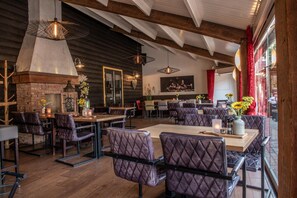 A restaurant interior with wooden beams, quilted leather chairs, and pendant lighting. - Herberg De Brabantse Kluis (Aarle-Rixtel)