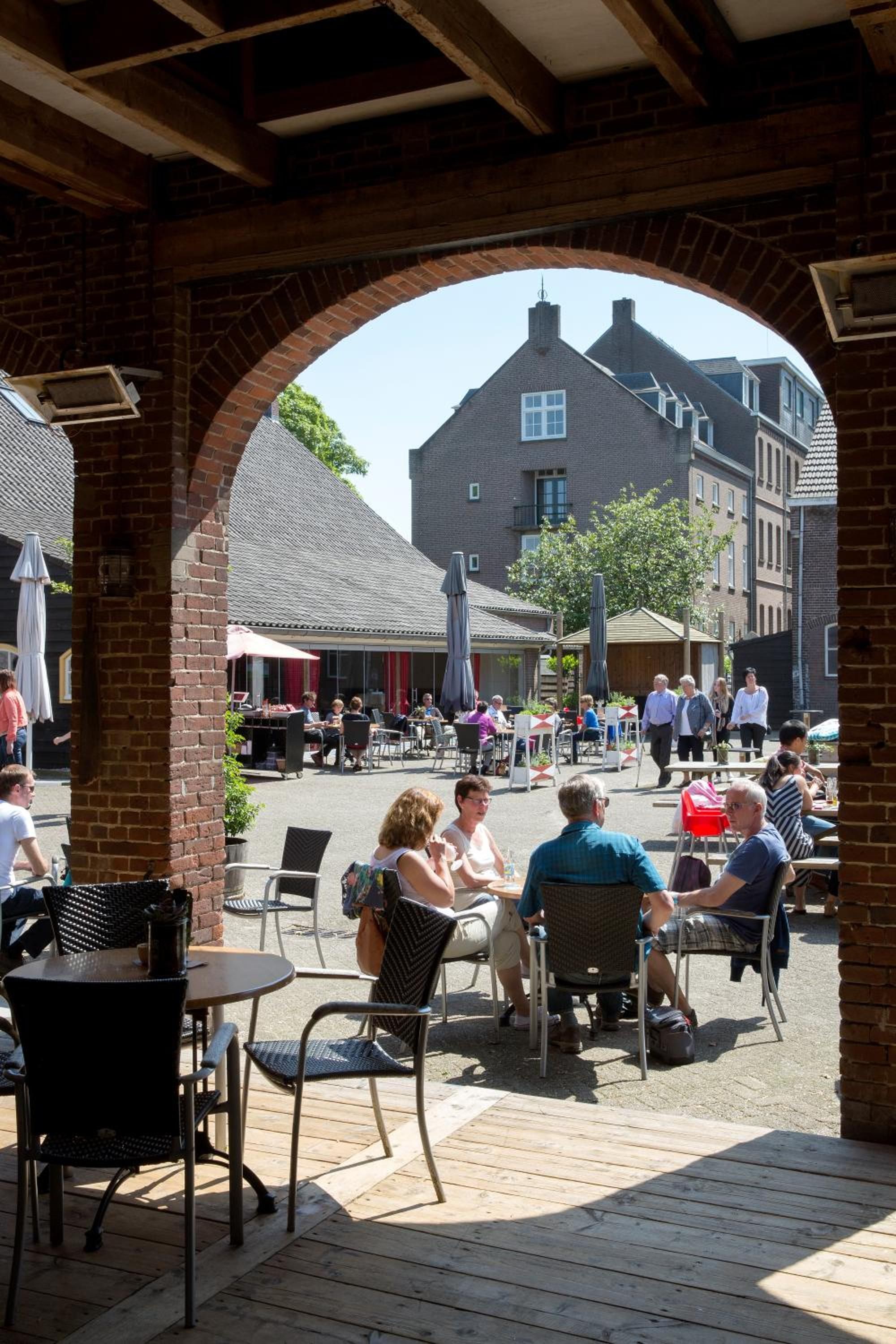 An outdoor café with brick arches, tables, and chairs.